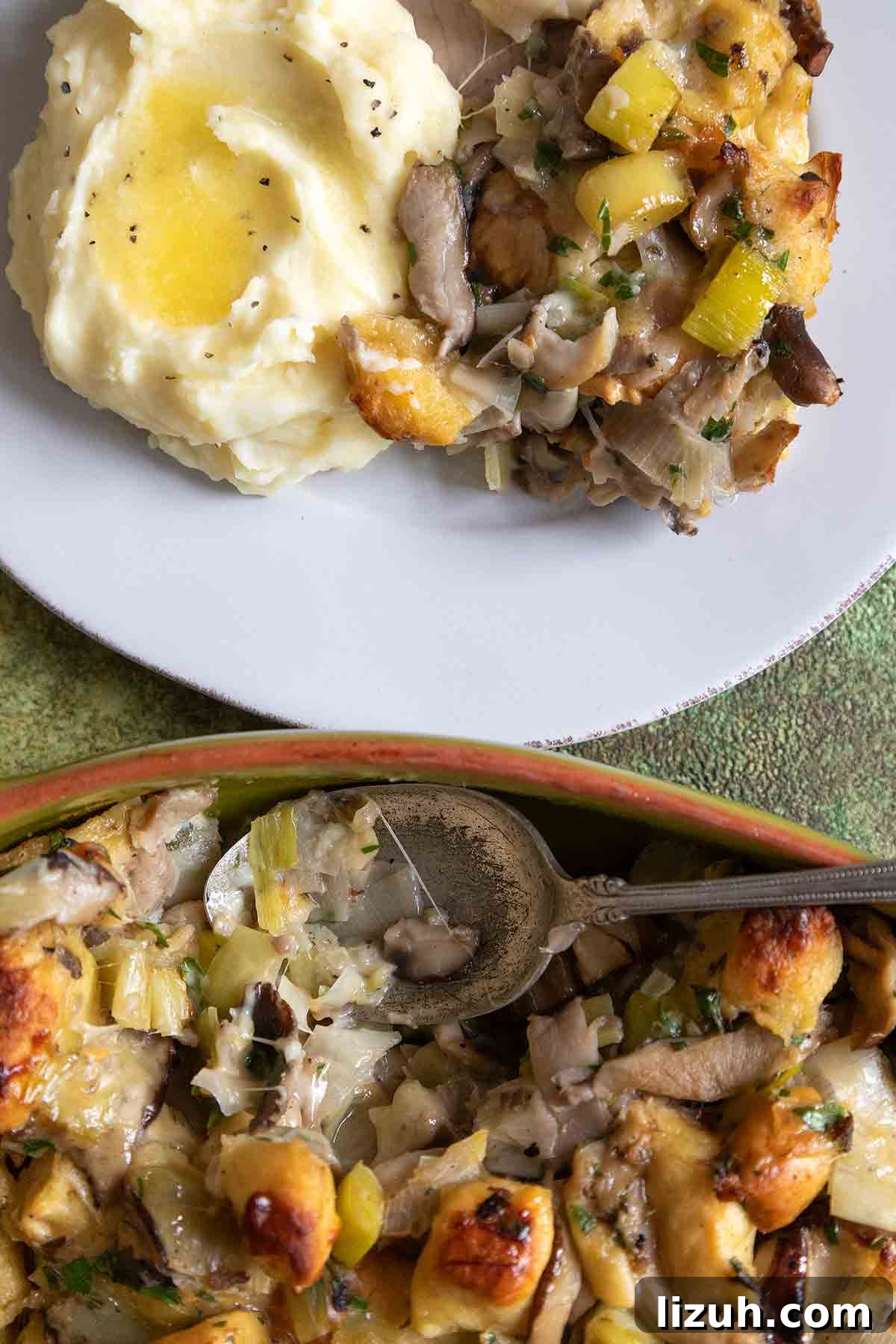 An oval casserole dish filled with wild mushroom stuffing and a plate of stuffing and mashed potatoes next to it.