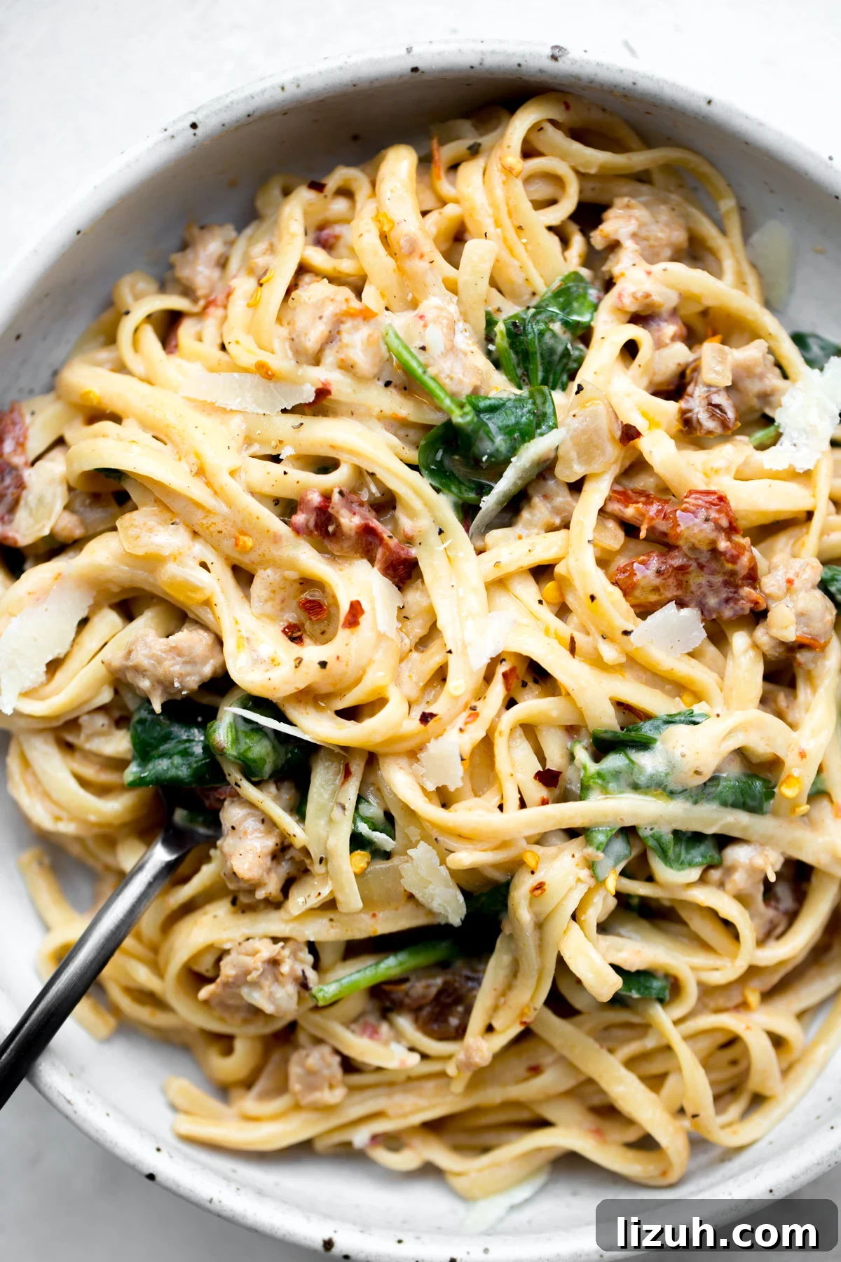 overhead shot of a bowl of instant pot sausage and sun-dried tomato linguine pasta on a white background