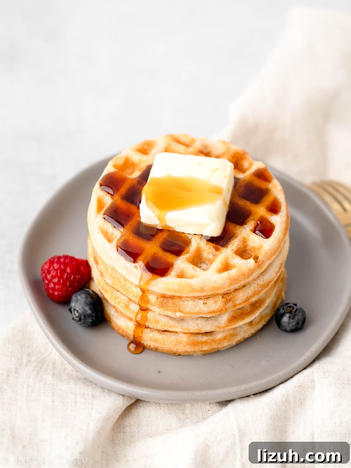 Gluten free waffles on a plate with butter and syrup. 