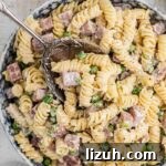 Ruby Tuesday-Style Ham and Pea Pasta Salad Recipe 12 Close up of a bowl of Ruby Tuesday ham and pea pasta salad with a spoon digging in.