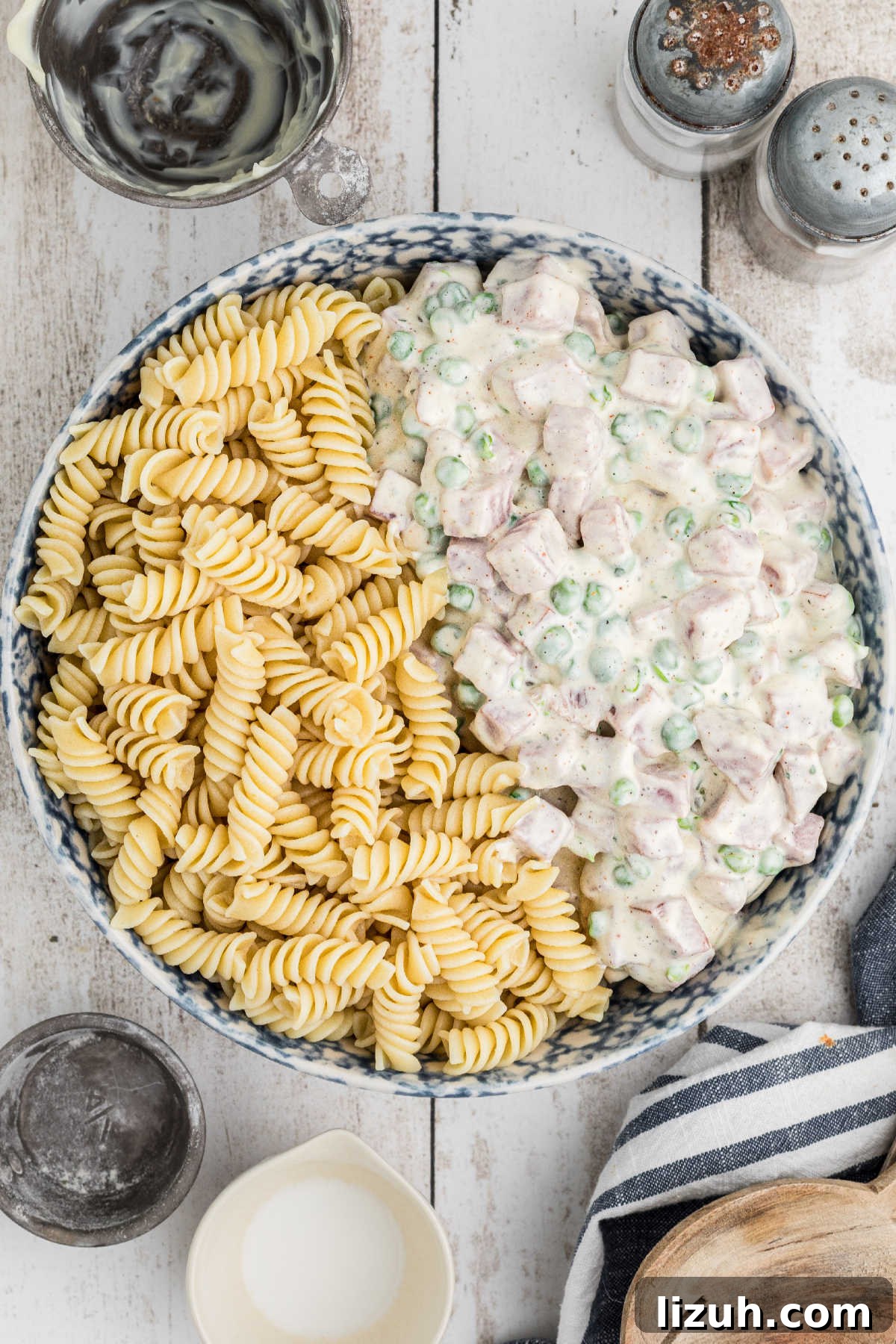 Ruby Tuesday-Style Ham and Pea Pasta Salad Recipe 7 A salad bowl, with half cooked pasta and half ham and pea dressing, about to be mixed together.