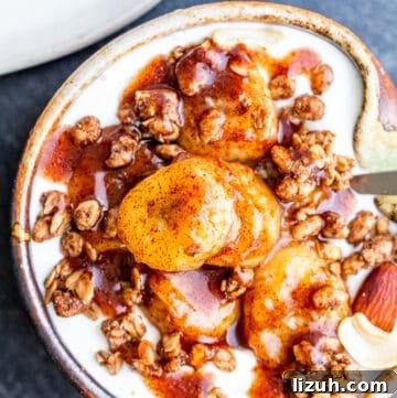 Overhead shot of bananas on top of granola and yogurt in small tan bowl.