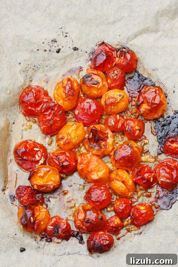 Slow-Roasted Tomato and Ricotta Bruschetta Recipe 5 Overhead image of red and orange roasted cherry tomatoes on a baking paper lined baking sheet.