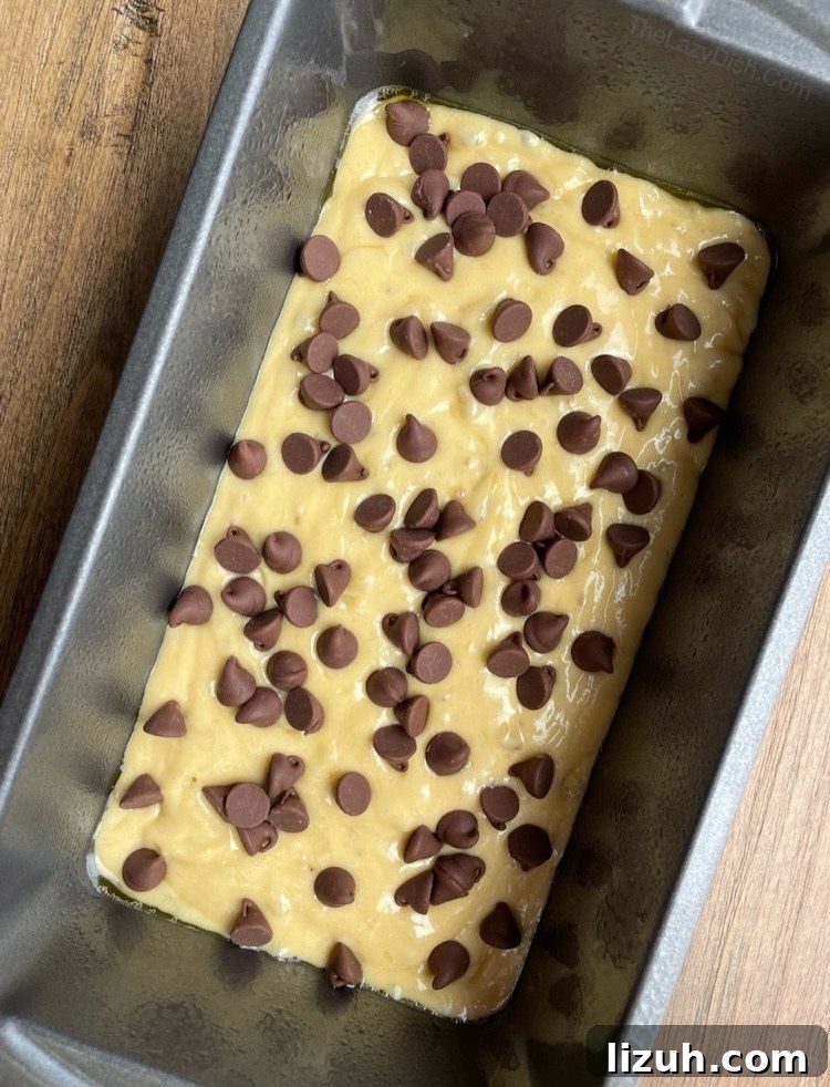 3-Ingredient Banana Bread Made with Cake Mix 6 Yellow cake mix banana bread in a bread pan with chocolate chips on top, ready for baking.