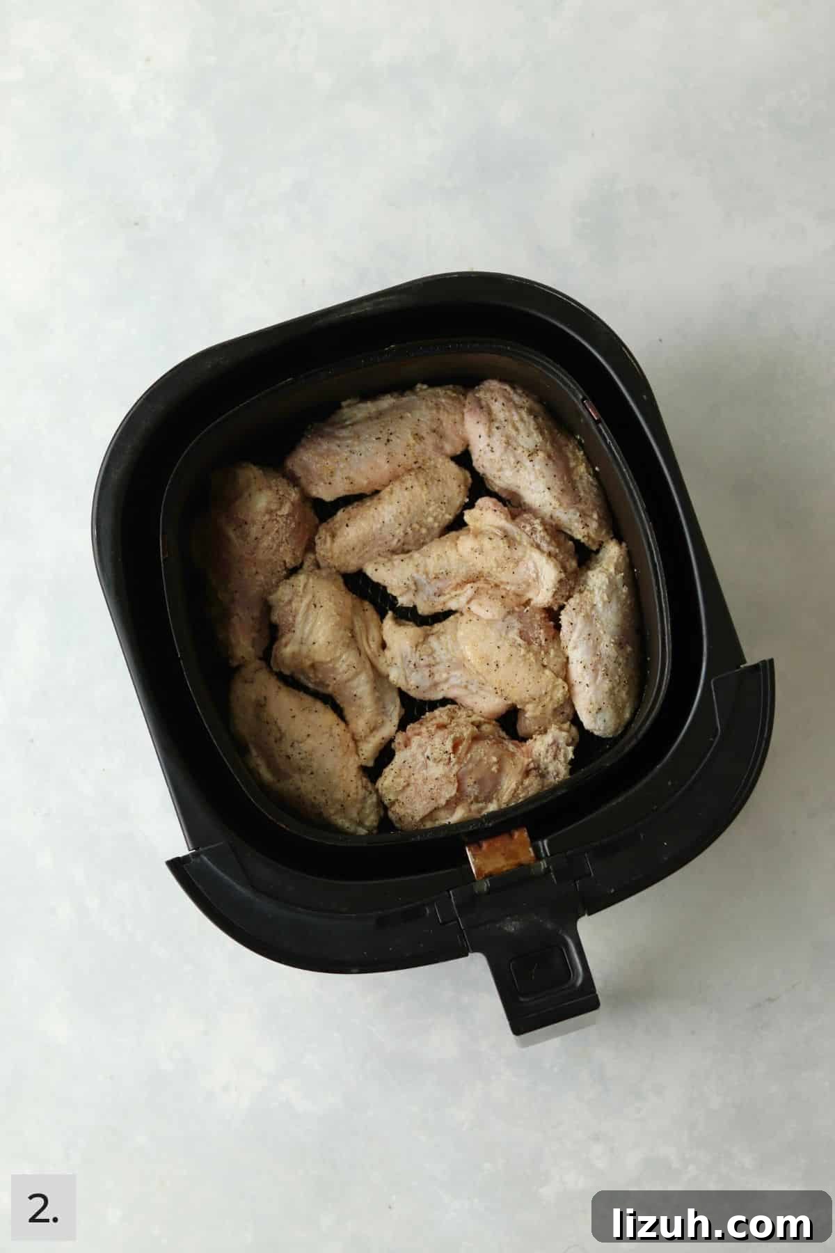 Crispy Garlic Parmesan Air Fryer Chicken Wings 5 Uncooked chicken wings tossed in spices in an air fryer.
