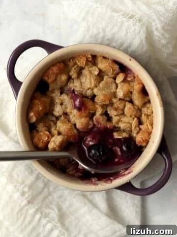 Single serve blueberry crisp in a ramekin with an oat topping.