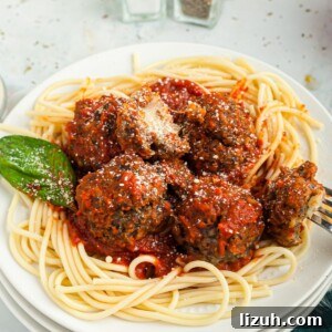 Cheese stuffed meatballs served over pasta on a white plate