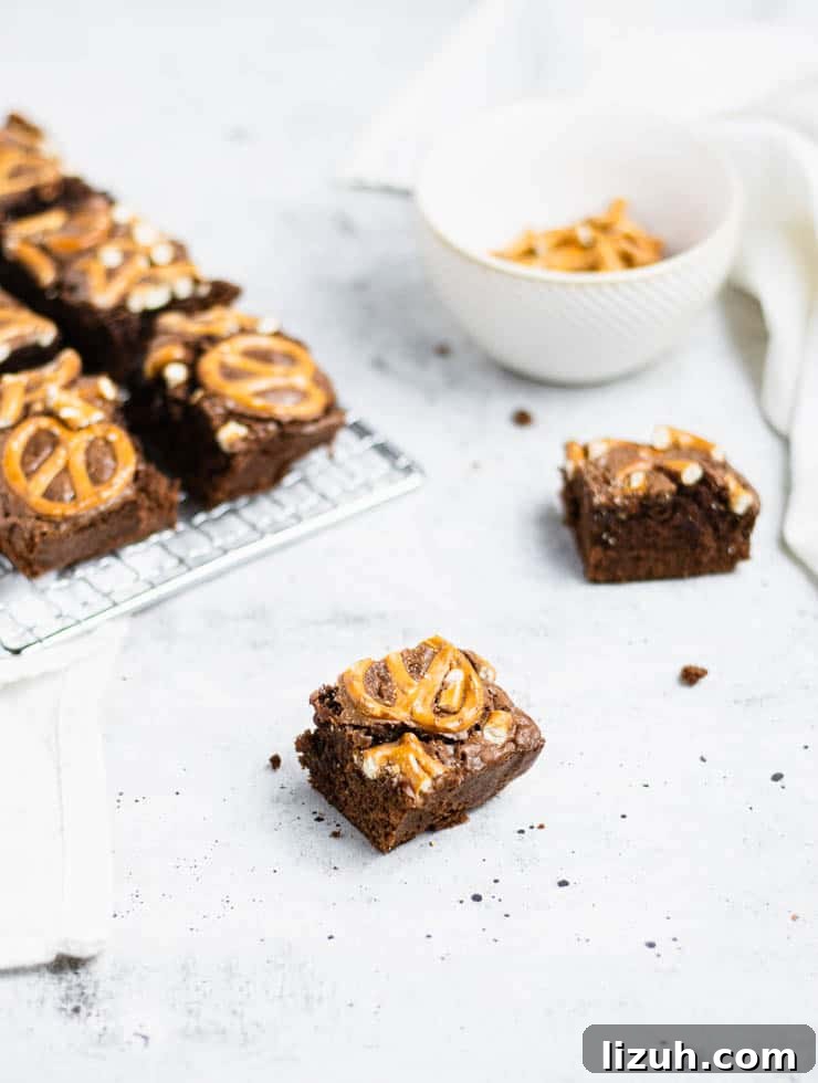 close up of pretzel topped stout brownie with more brownies and a bowl of pretzels in the background