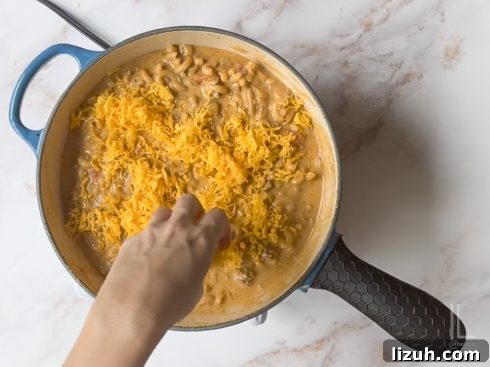 One-Pot Taco Mac and Cheese Recipe for Quick Weeknight Dinners 9 sprinkling cheddar cheese over the top of the cooked taco mac and cheese.