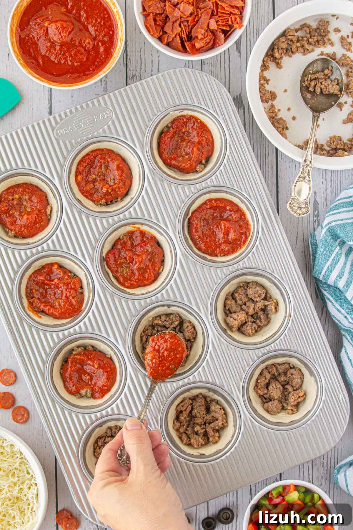 Mini Pizza Cups Recipe: Homemade Pizza Bites in 30 Minutes 5 Spooning pizza sauce over the ground beef in the pizza cups.