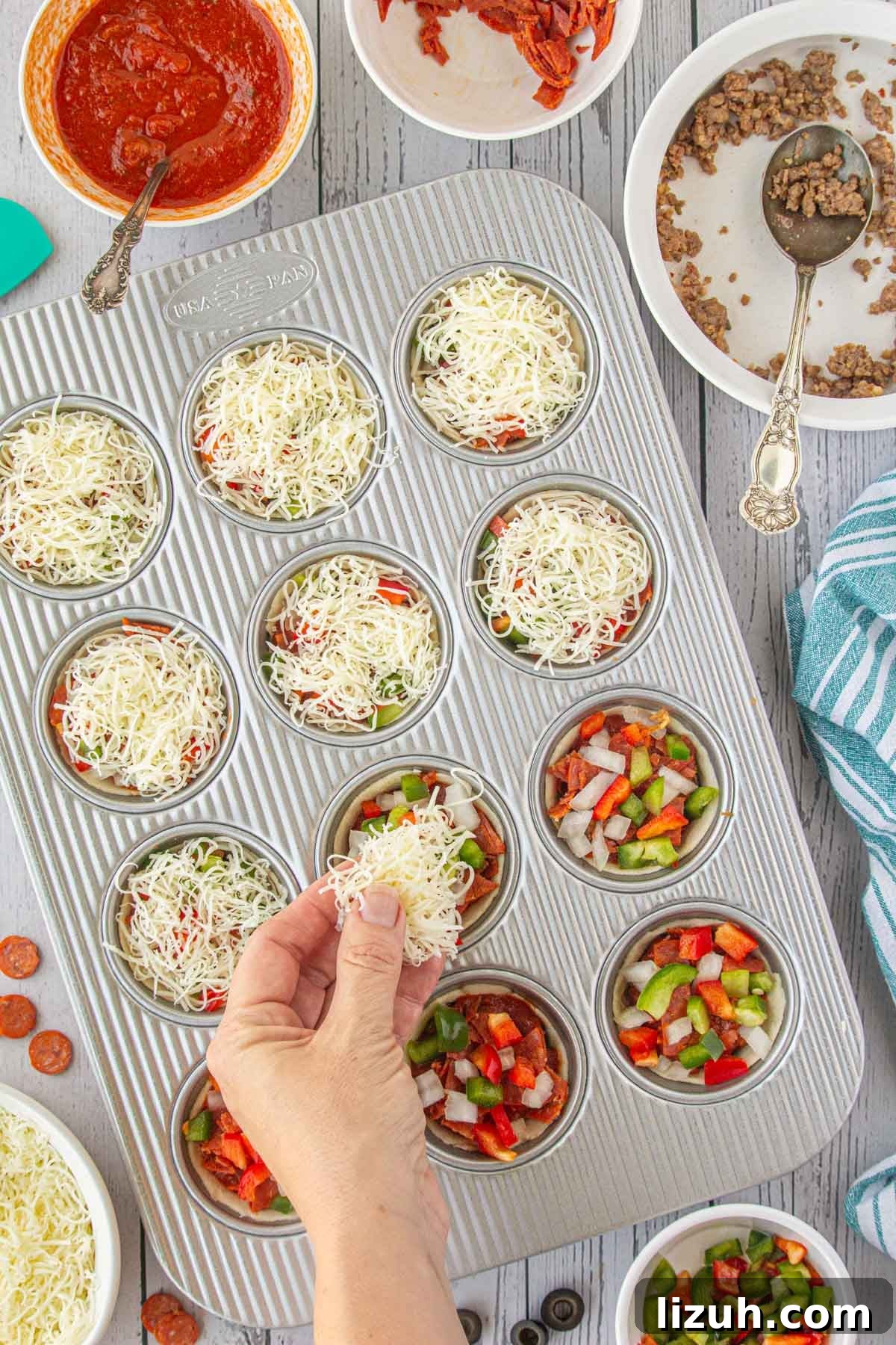Mini Pizza Cups Recipe: Homemade Pizza Bites in 30 Minutes 7 Adding cheese to the pizza cups.