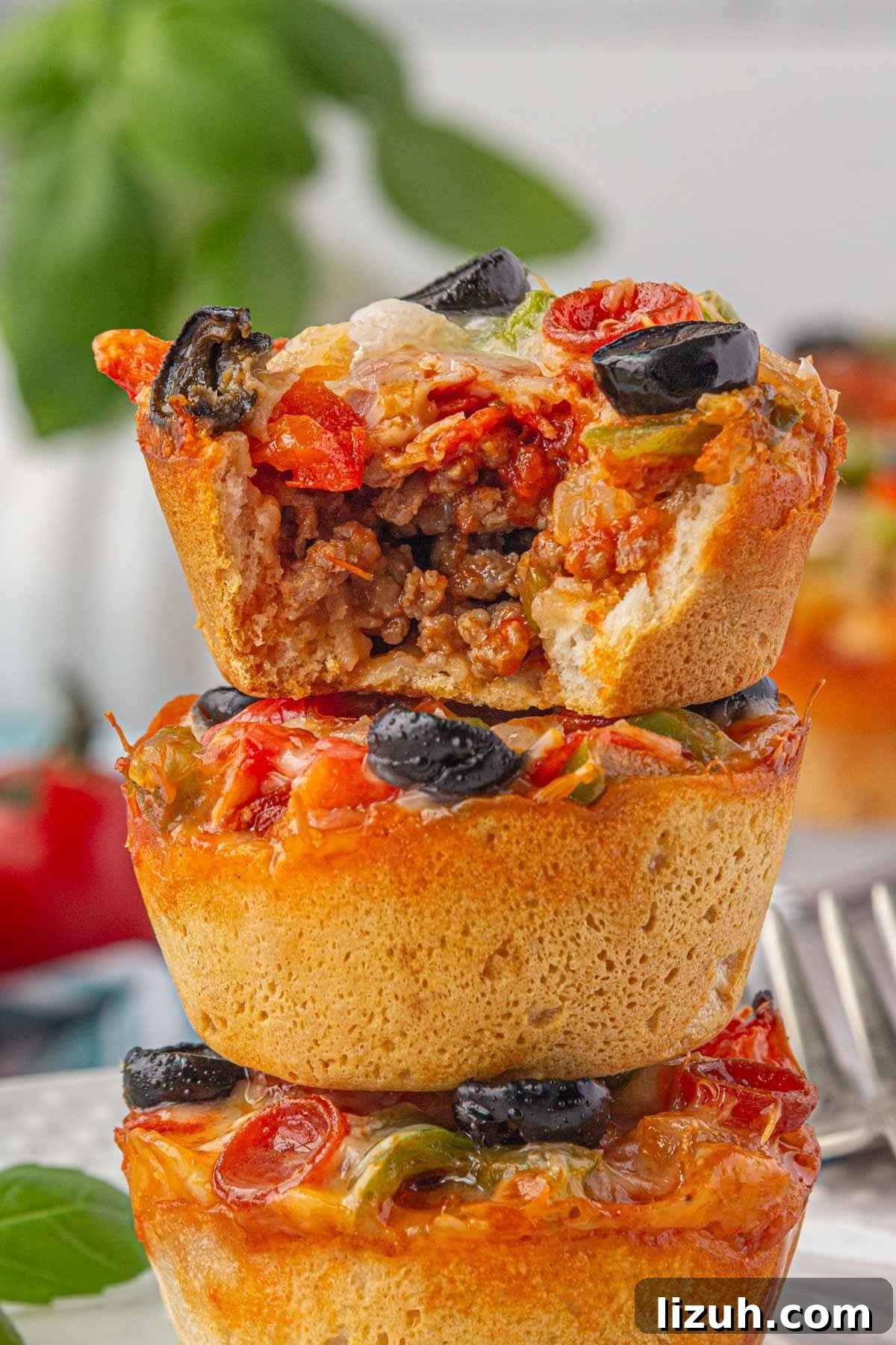 Mini Pizza Cups Recipe: Homemade Pizza Bites in 30 Minutes 10 A close-up, side view of three pizza cups stacked on one another, with a a bite taken out of the top pizza cup.