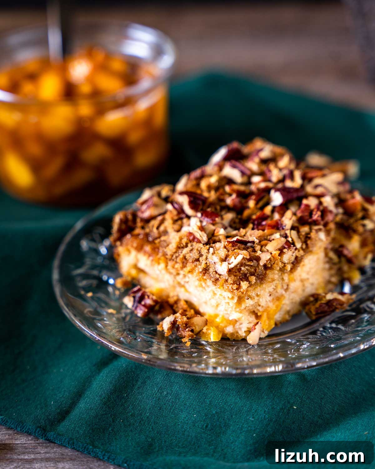 Single slice of fresh peach cobbler with crunchy pecan topping.