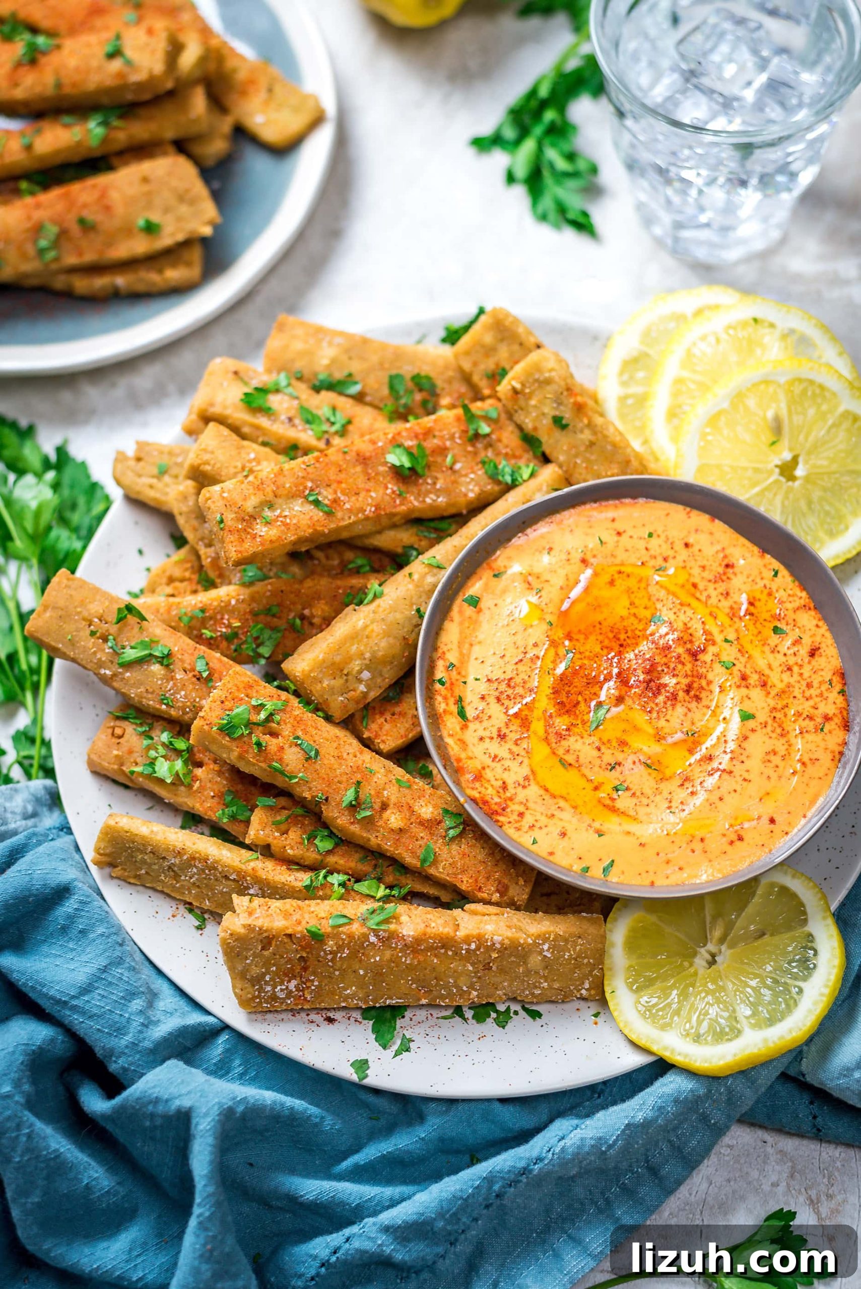 Hummus Fries with Spicy Tahini Dipping Sauce 6 Hummus Fries with Spicy Tahini Dip on a round, white plate with a blue cloth below.