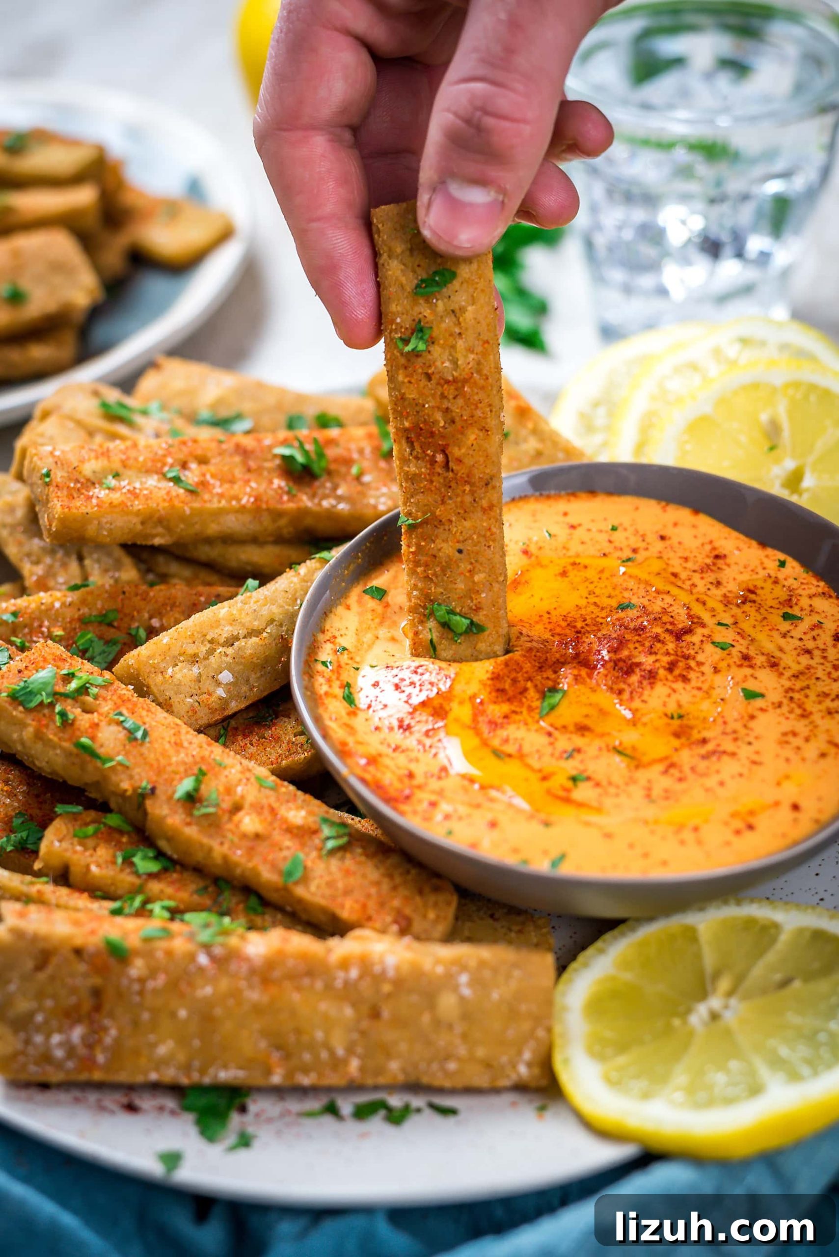 Hummus Fries with Spicy Tahini Dipping Sauce 7 A hand dipping a Hummus Fry into Spicy Tahini Dip.