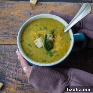 Creamy Fiddlehead and Cheese Soup Recipe 20 fiddlehead soup in a mug with a spoon in it and hands cradling it