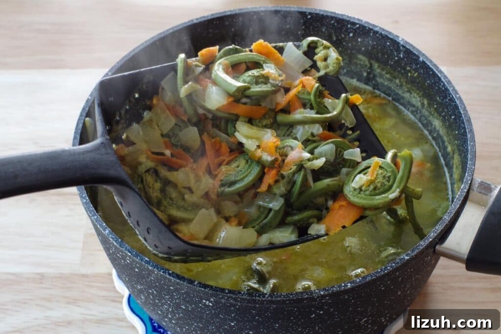 Creamy Fiddlehead and Cheese Soup Recipe 8 vegetables being removed with a slotted spoon