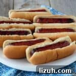 glazed smoked sausages in buns on white plate