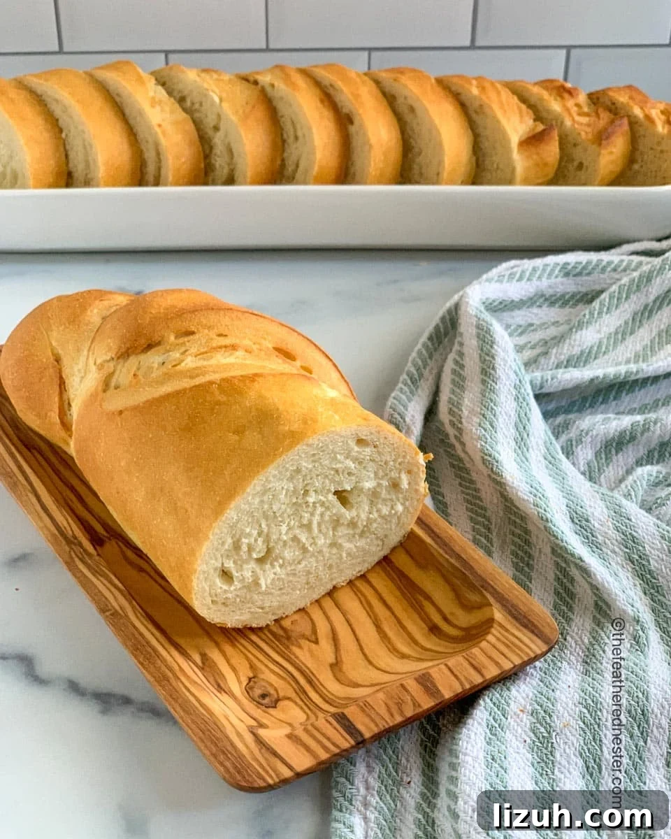 Crisp-Crust Sourdough French Bread Recipe for Rustic Loaves 7 A cut loaf of French bread with slices in the background.
