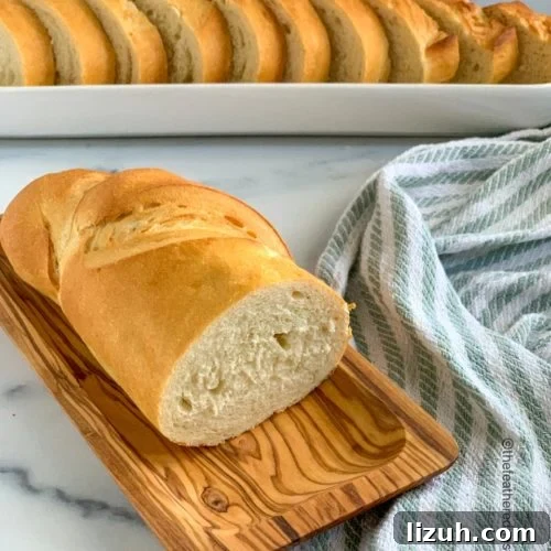 Crisp-Crust Sourdough French Bread Recipe for Rustic Loaves 8 a cut loaf of French bread with slices in the background.