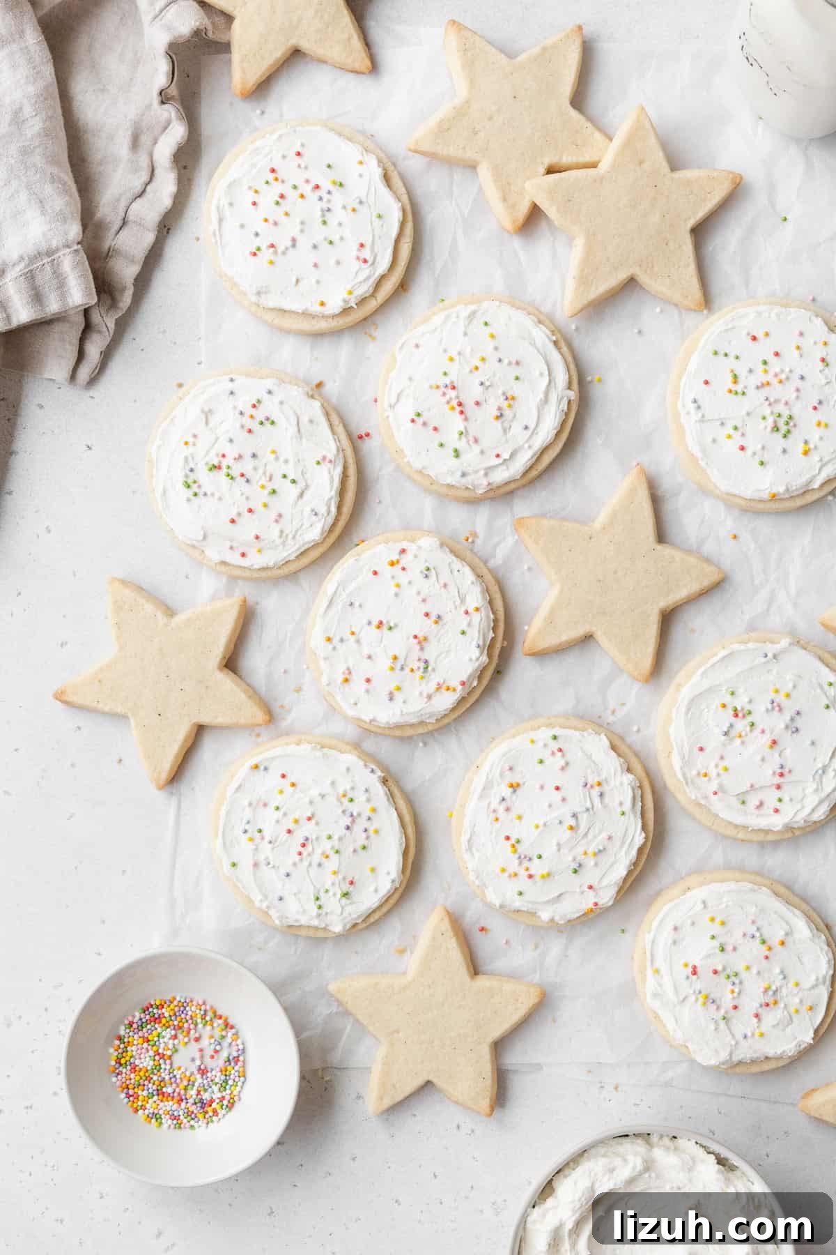 Gluten-Free Sugar Cookie Recipe for Crisp, Chewy Cookies 12 Star shaped sugar cookies and round frosted gluten free cookies laid out on a white surface.