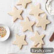 Gluten-Free Sugar Cookie Recipe for Crisp, Chewy Cookies 15 Star shaped gluten free sugar cookies on a white surface next to a small dish of sprinkles and a bowl of frosting.
