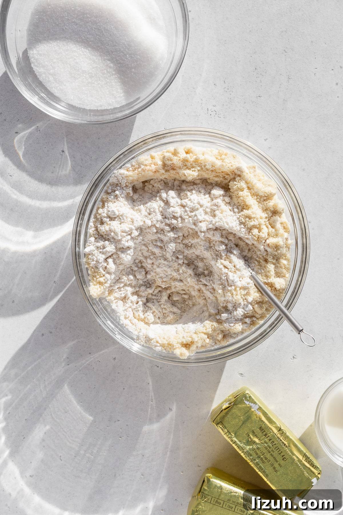 Gluten-Free Sugar Cookie Recipe for Crisp, Chewy Cookies 4 Dry ingredients mixed together in a glass bowl on a light grey surface.