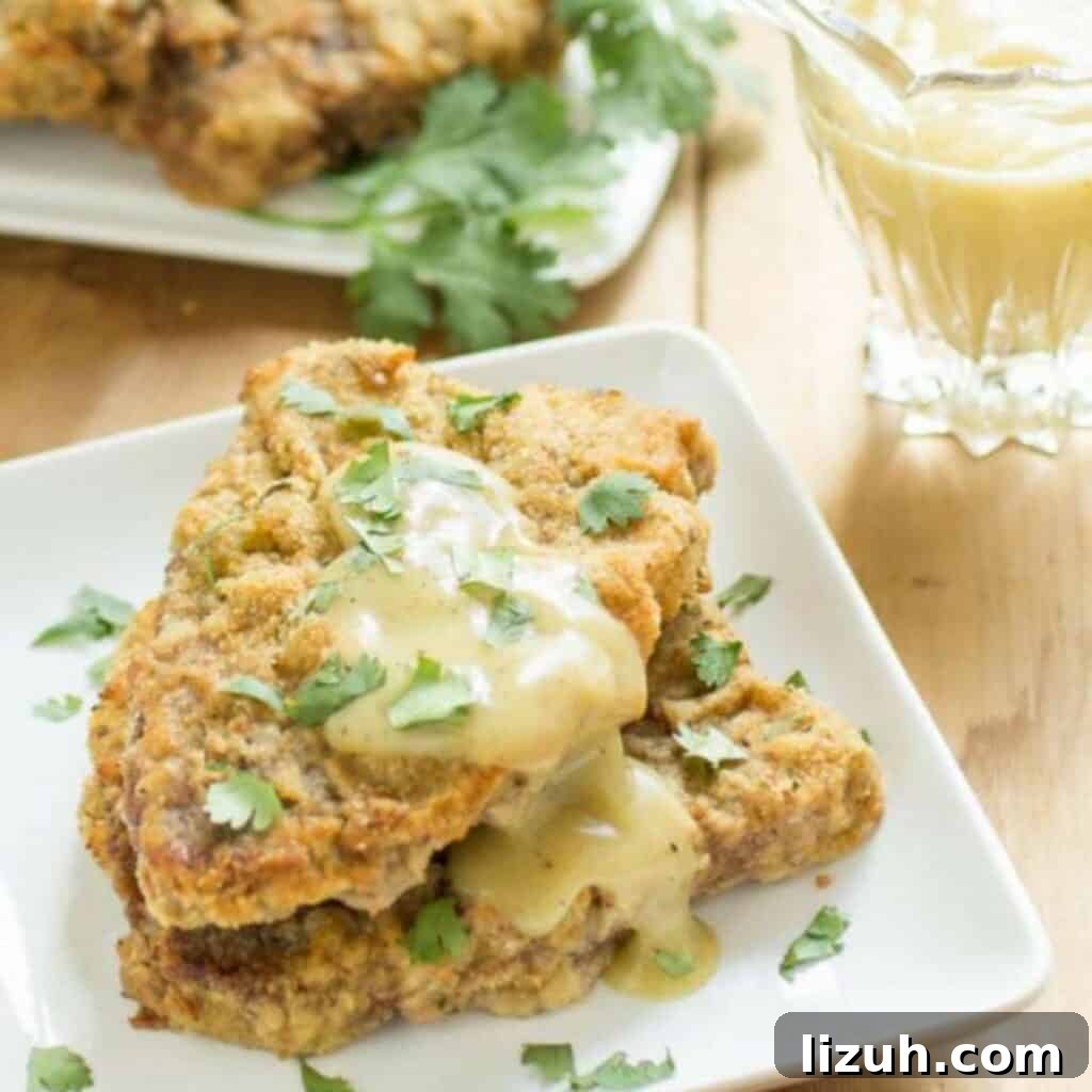 41 Perfect Side Dishes to Serve with Biscuits and Gravy 27 two chicken fried steaks on a plate with a bit of gravy and herbs.