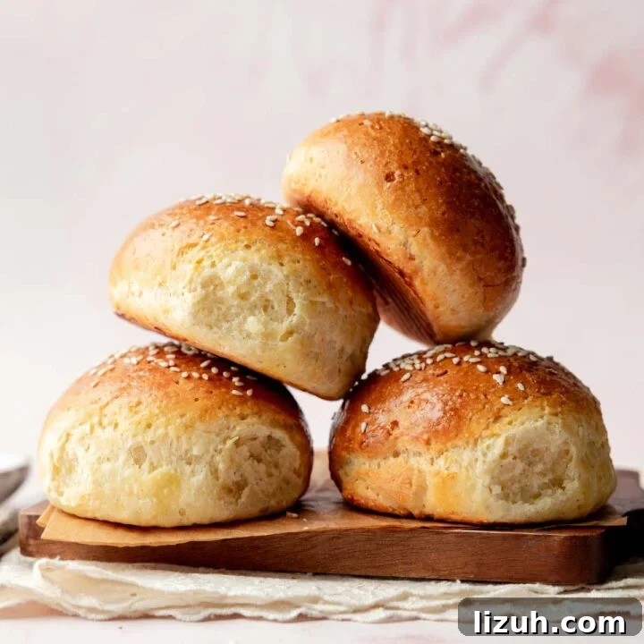 Stack of fluffy gluten-free hamburger buns with sesame seed topping.