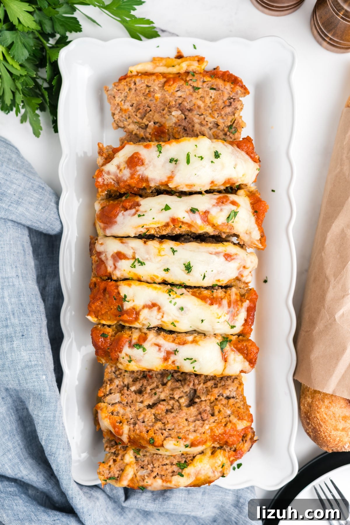 Italian meatloaf sliced up on a platter and topped with sauce and mozzarella cheese. 