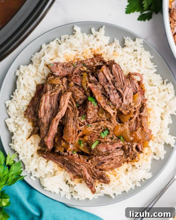 Crockpot skirt steak shredded and served over a plate of rice.