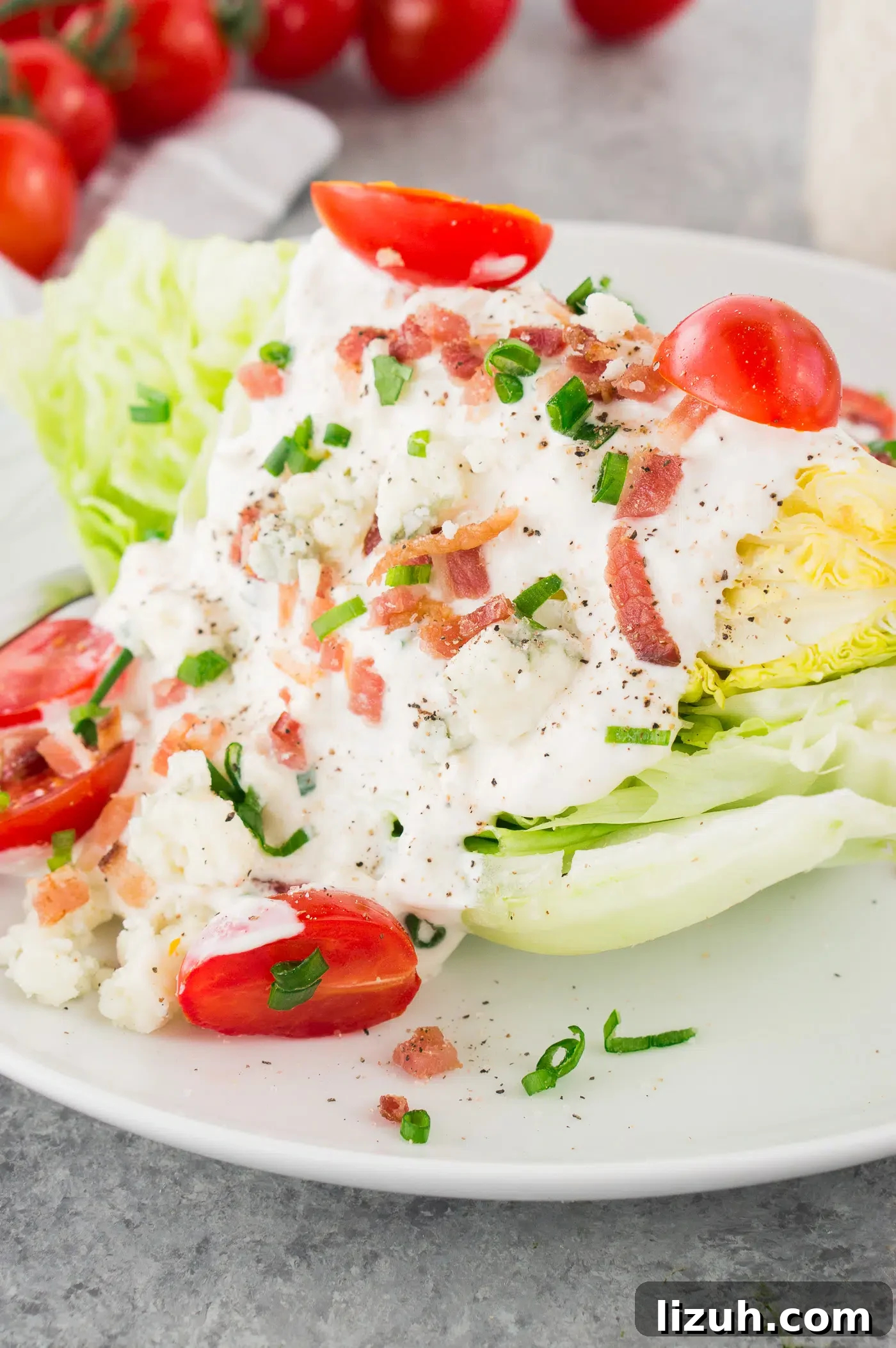 Classic Wedge Salad Recipe with Creamy Blue Cheese Dressing 7 close up shot of iceberg wedge salad drizzled with blue cheese dressing tomatoes and bacon served on a plate
