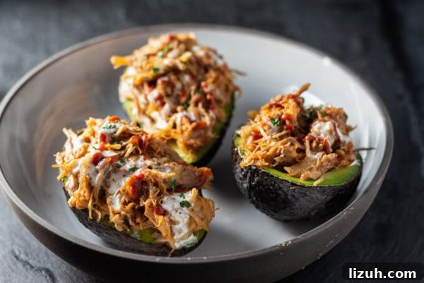 Keto Pulled Pork Stuffed Avocado Boats: Low-Carb Recipe 4 Stuffed avocados or avocado boats with pulled pork, cheese, and BBQ sauce in a bowl.