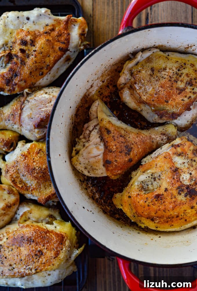 Chicken Pieces browning in a red dutch oven with cooked chicken pieces next to it.
