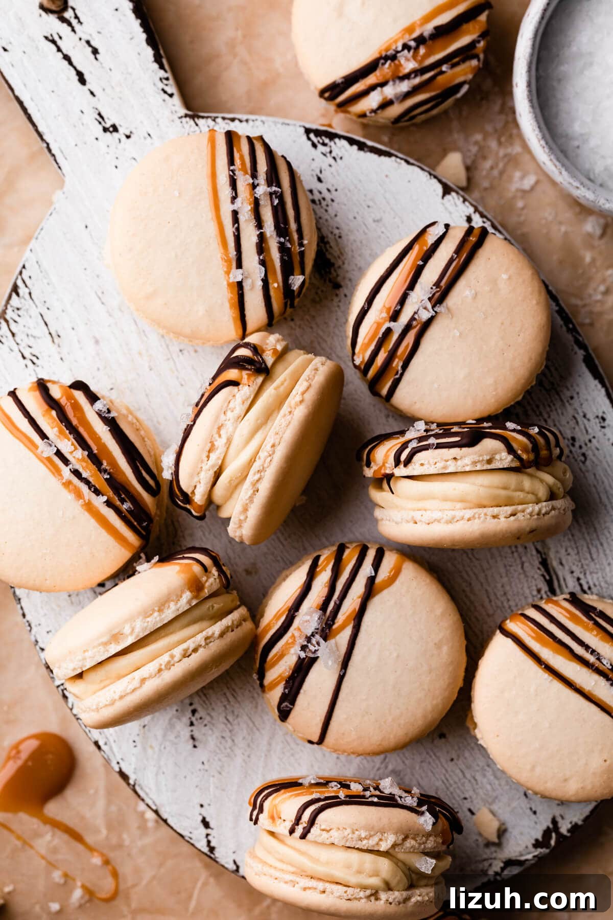 Irresistible Salted Caramel Macarons Recipe for Perfect Results 13 caramel macarons topped with chocolate and caramel drizzle and some sea salt flakes.