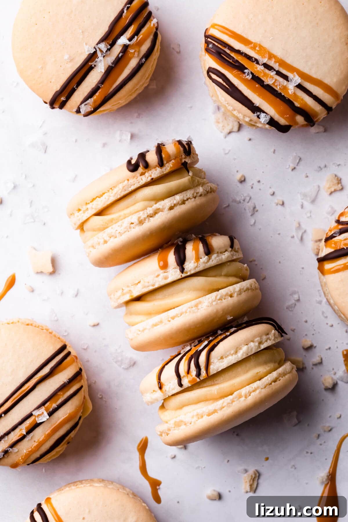 Irresistible Salted Caramel Macarons Recipe for Perfect Results 14 salted caramel macarons with crumbs and sea salt flakes around them.
