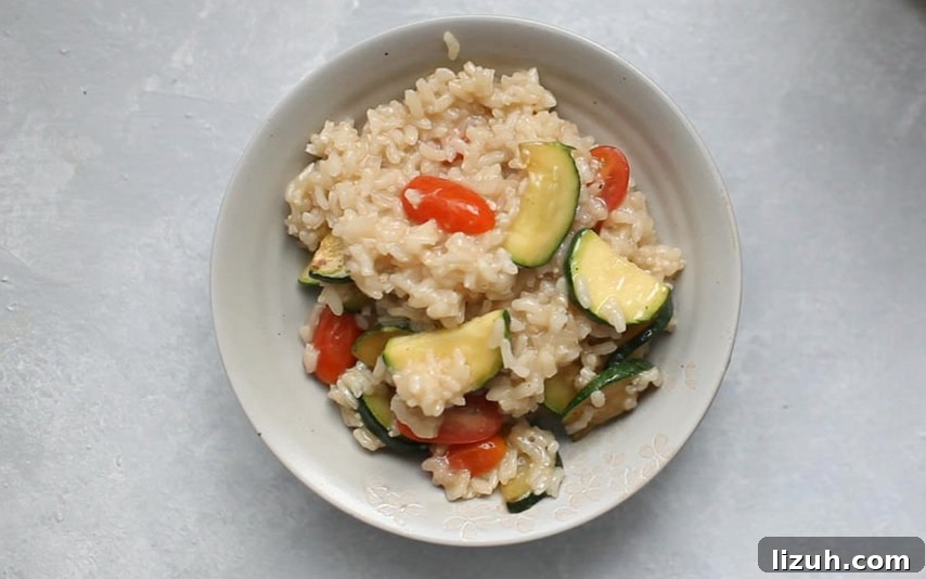 A bowl of risotto with zucchini and tomatoes.