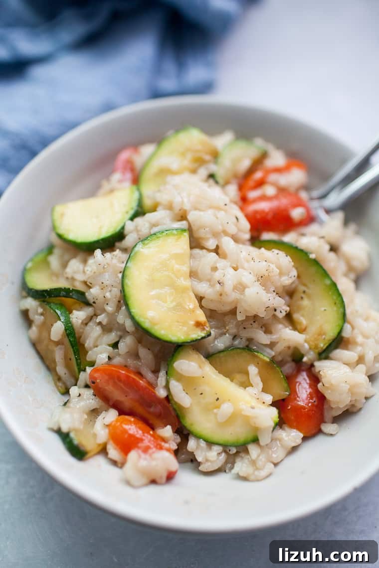 Gray bowl with vegetable risotto on top of a blue linen napkin.