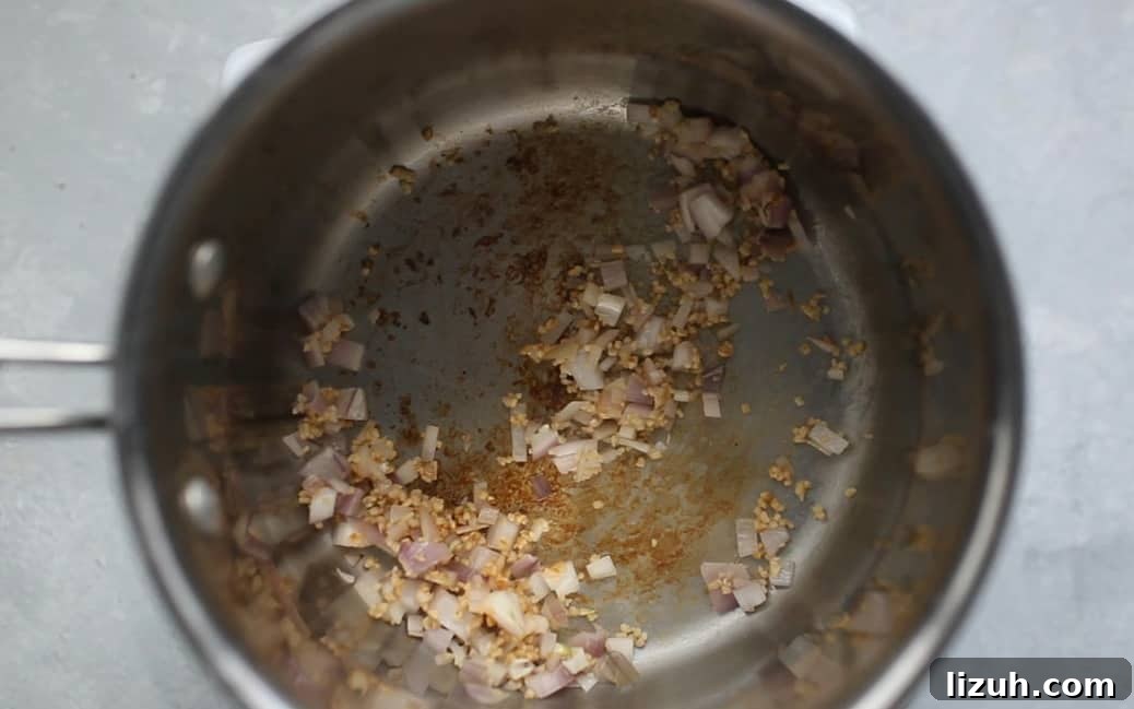 A pot with sautéed onions and garlic in it.
