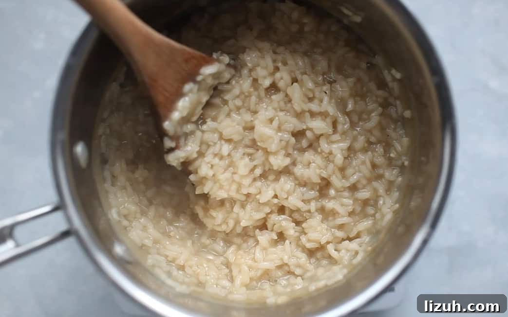 Risotto in a pot being stirred by a wooden spoon.