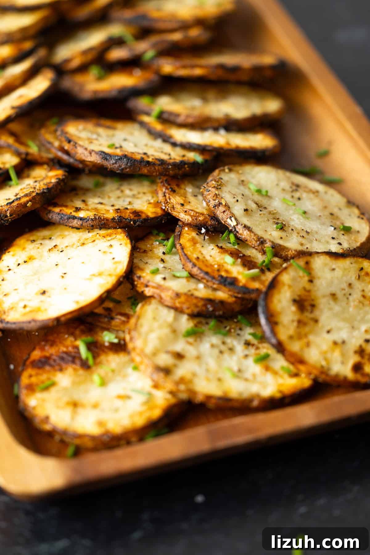 Crispy Grilled Sliced Potatoes Recipe for Summer BBQs 2 Grilled sliced potatoes on a wooden serving board.