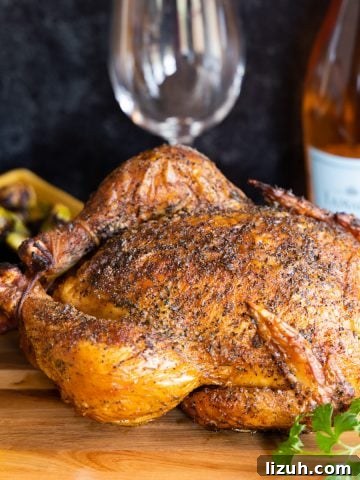 Smoked whole chicken on cutting board with lemon and bottle of wine in background.