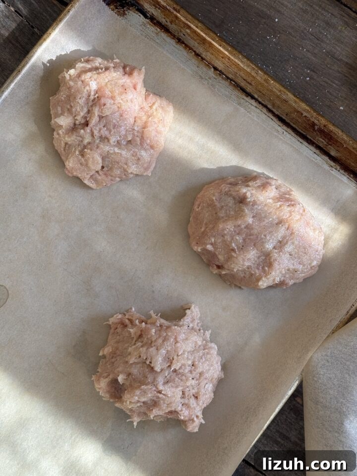 Quick Weeknight Ground Chicken Burgers Recipe 7 a photo of ground chicken burgers formed on a parchment lined baking sheet