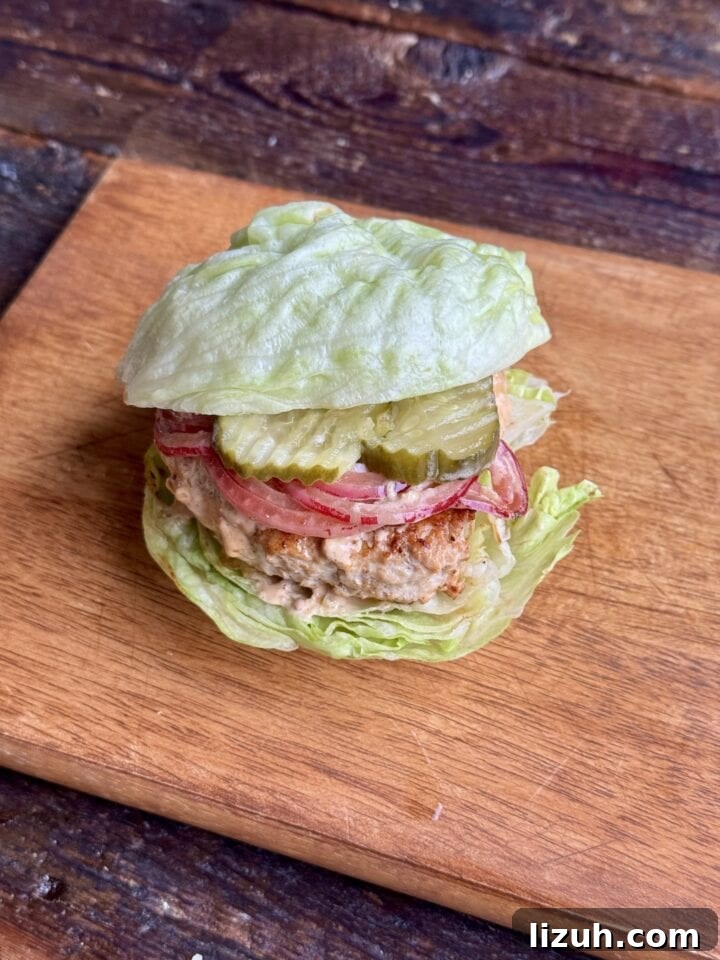 Quick Weeknight Ground Chicken Burgers Recipe 10 a photo of a ground chicken burger on a lettuce bun on a cutting board