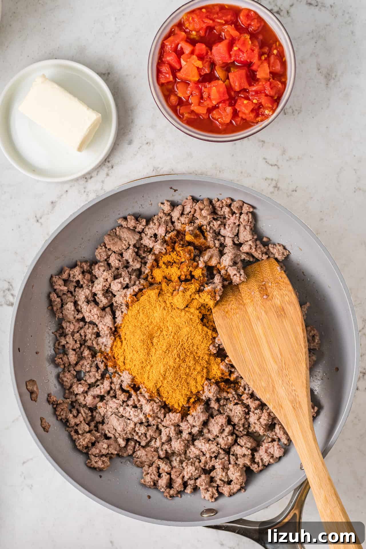 Cooked ground beef in a skillet with taco seasoning.