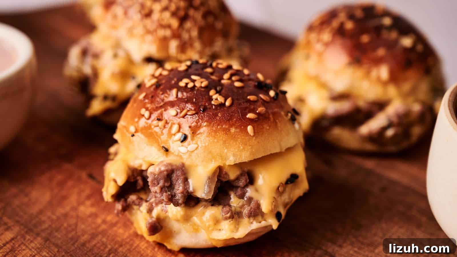35 Game-Day Recipes to Win Your Season’s Food Lineup 13 Three sesame seed buns filled with melted cheese and ground beef are arranged on a wooden board.
