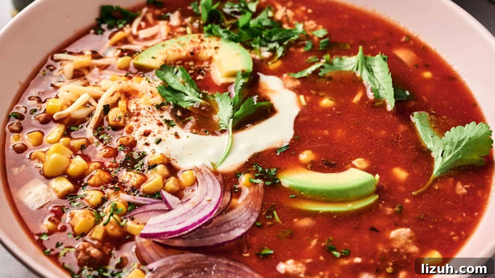 35 Game-Day Recipes to Win Your Season’s Food Lineup 14 A bowl of red soup topped with avocado slices, sour cream, cilantro, sliced onions, corn, and shredded cheese.
