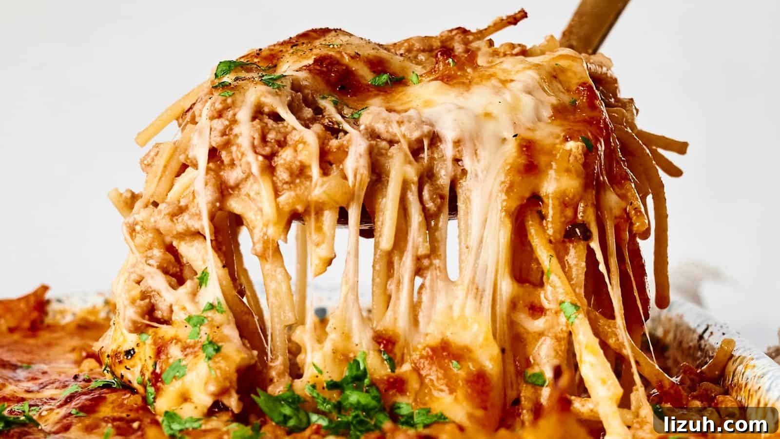 35 Game-Day Recipes to Win Your Season’s Food Lineup 19 A serving of cheesy baked spaghetti is being lifted with a utensil. The dish is topped with melted cheese and garnished with herbs.