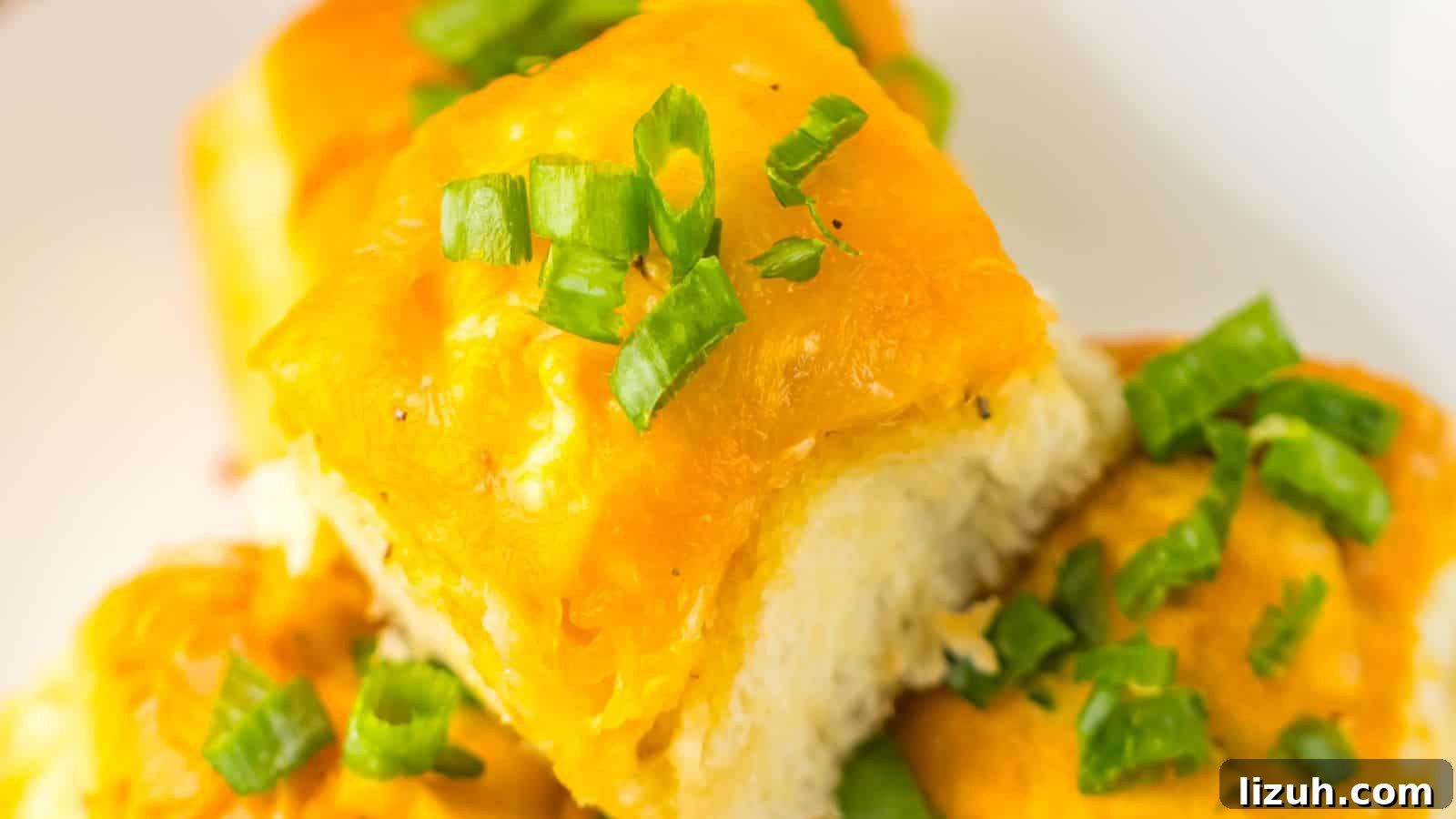 35 Game-Day Recipes to Win Your Season’s Food Lineup 26 Close-up of cheesy garlic bread rolls topped with chopped green onions on a white plate, reminiscent of Loaded Buffalo Chicken Rolls.