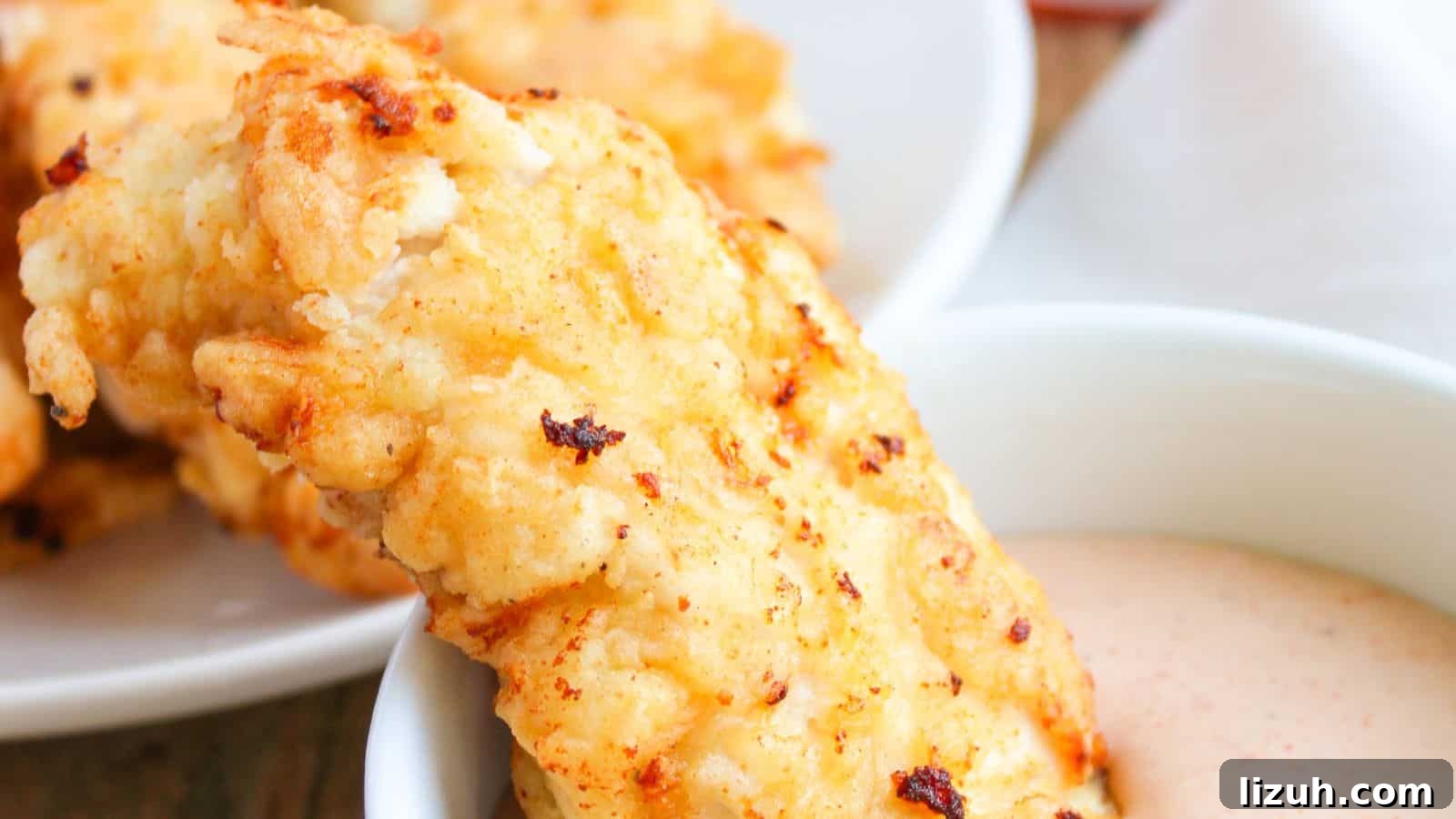 35 Game-Day Recipes to Win Your Season’s Food Lineup 30 A breaded and golden-brown fried chicken tender being dipped into a white sauce in a bowl, with more chicken tenders in the background.